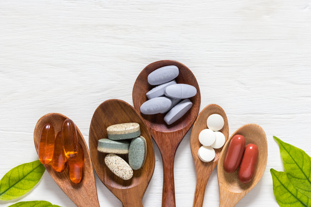 Variety,Of,Vitamin,Pills,In,Wooden,Spoon,On,White,Background